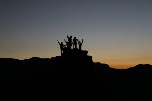 People standing on a hill arms raised