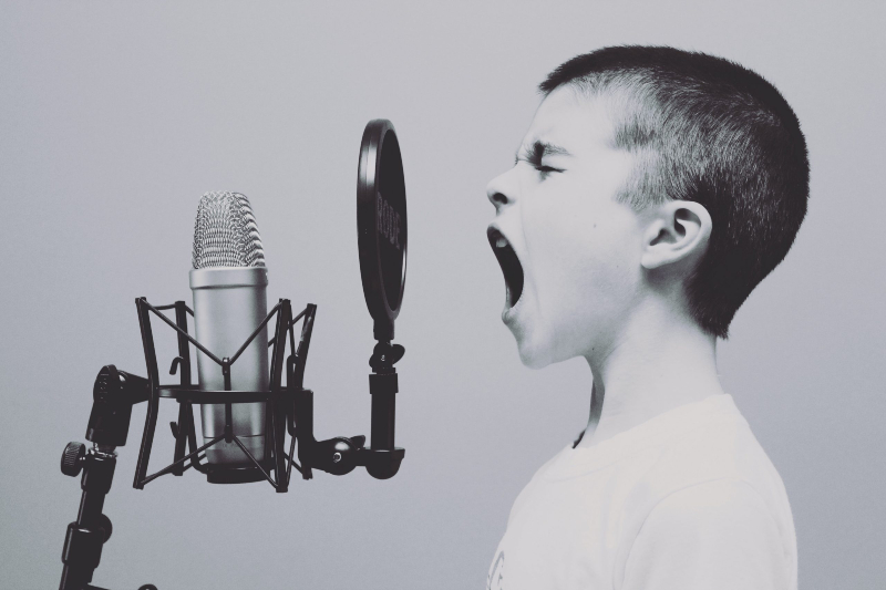 Boy yelling into microphone using his voice